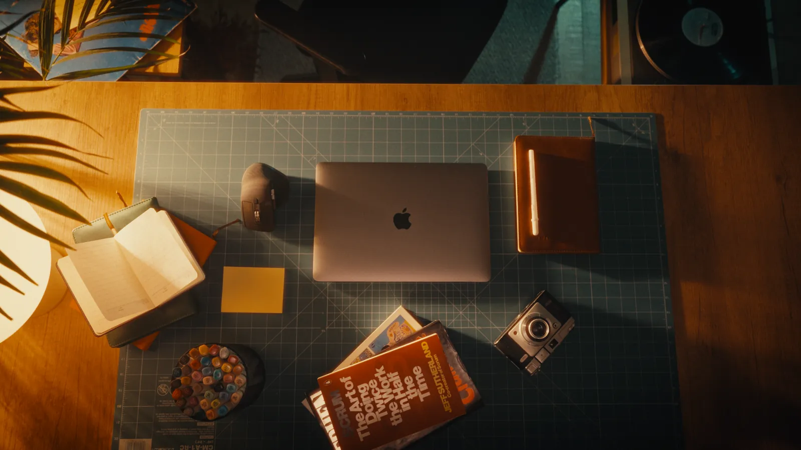 The studio desk from above with nobody at it: laptop, books, camera and notes